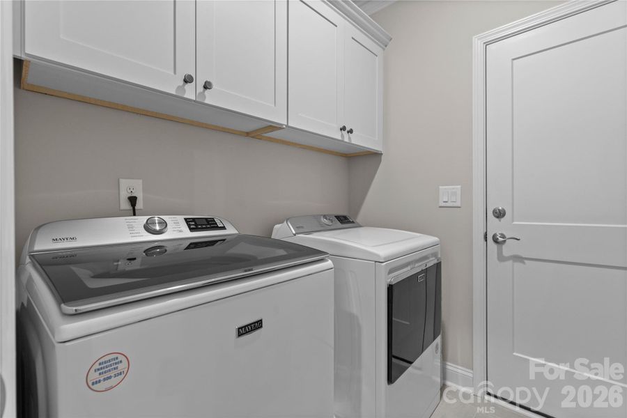 Laundry room with upper cabinetry leads to garage.