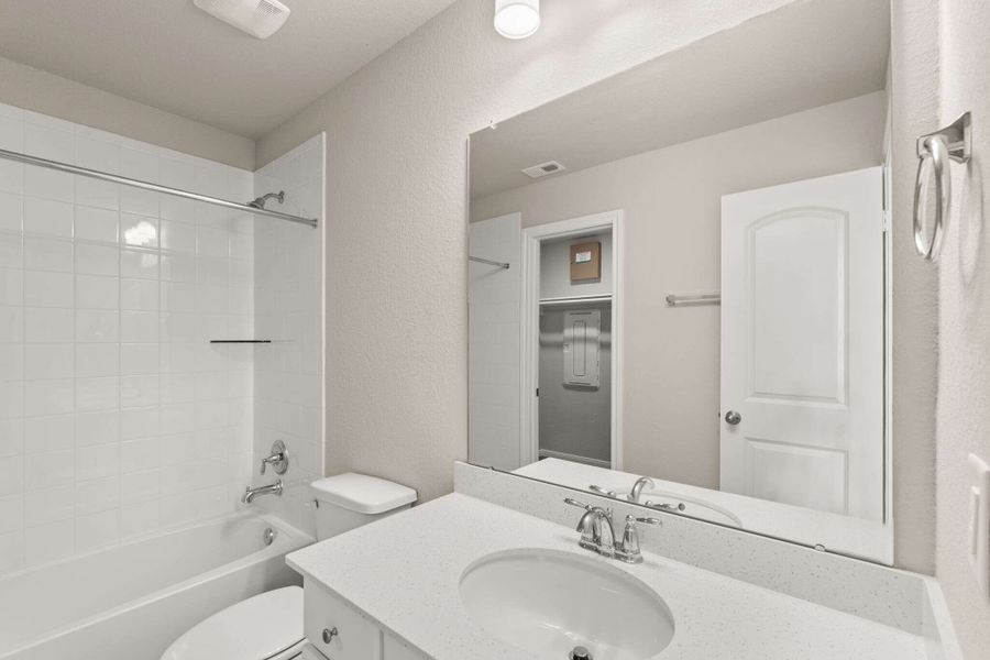 The private bath features white cabinetry with light countertops and a shower/tub combo.