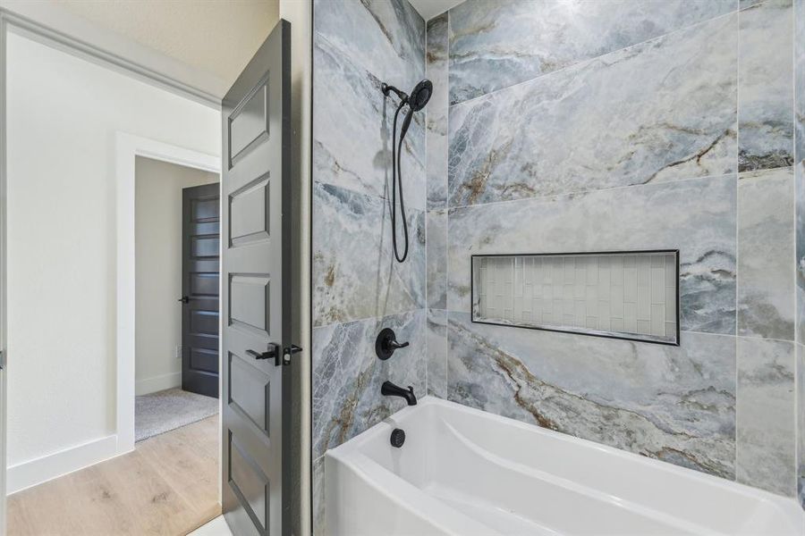 Bathroom with wood-type flooring and tiled shower / bath combo