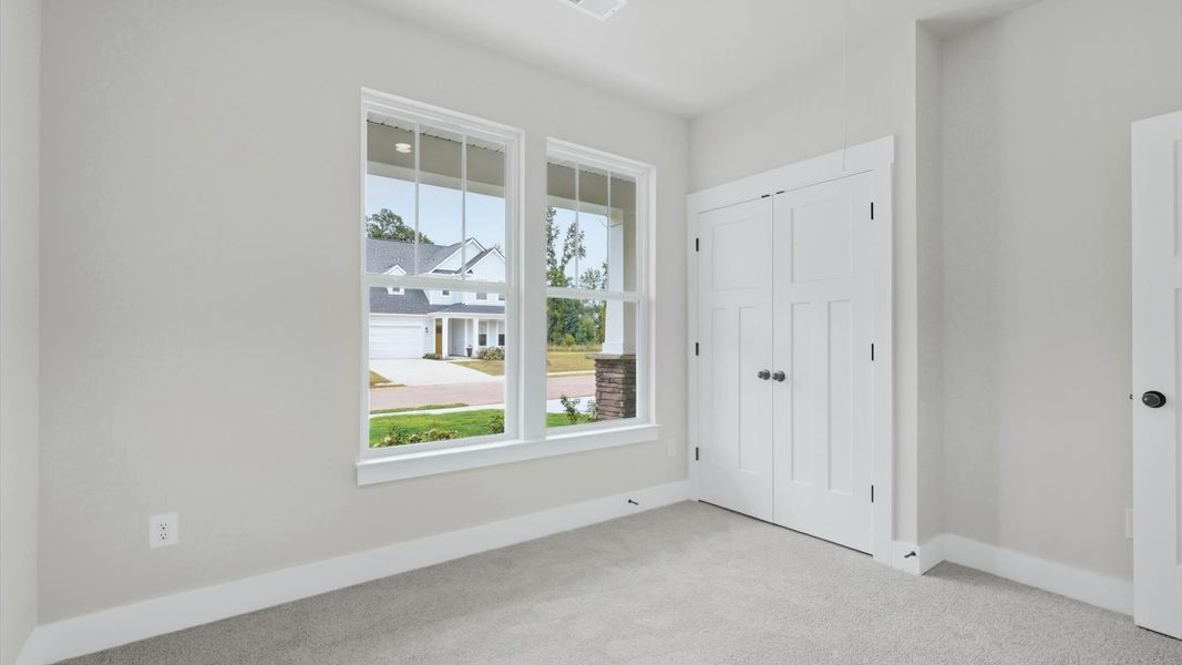 Refined bedroom design with large windows for daylight-filled mornings and peaceful views by DRB Homes