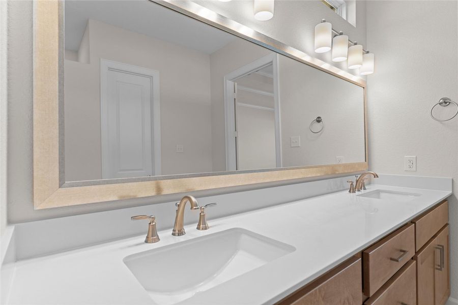 A closer look at the dual sink vanity reveals generous counter space, classic cabinetry, and bright lighting, creating a functional and elegant space ideal for busy mornings or quiet evenings.