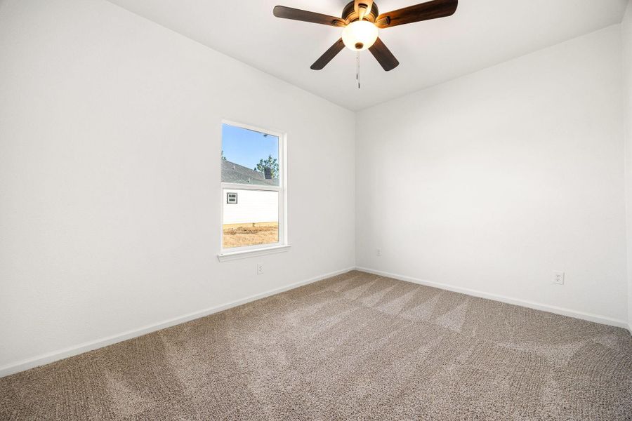 A bright bedroom featuring plush carpeting, a modern ceiling fan, and ample natural light. A bright bedroom featuring plush carpeting, a modern ceiling fan, and ample natural light.