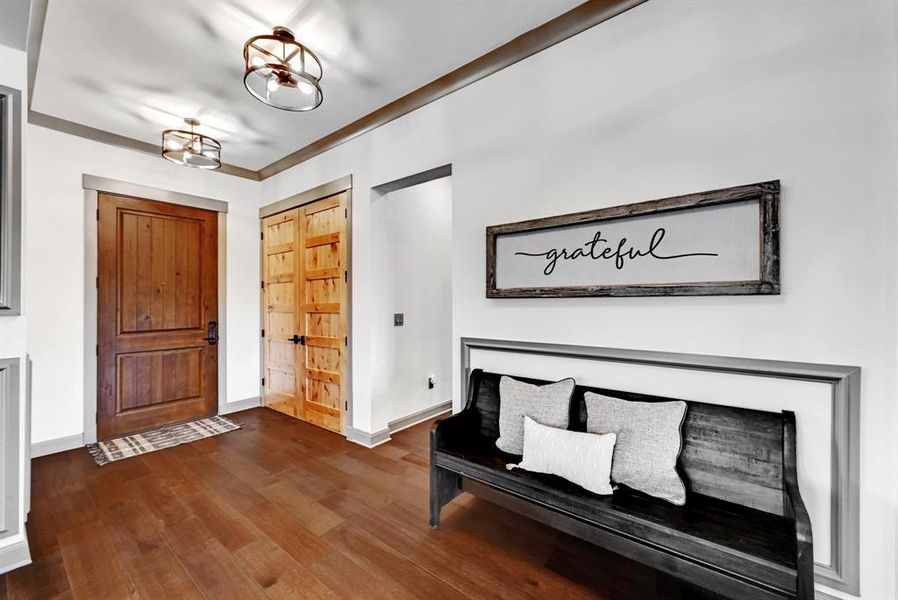 Foyer with wood finished floors, ornamental molding, and a chandelier