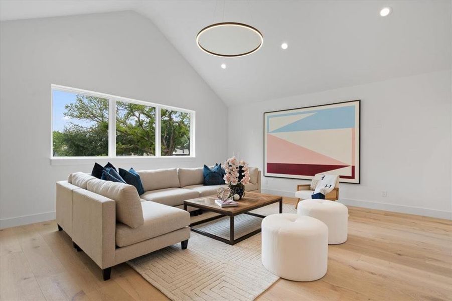 Living room featuring high vaulted ceiling and light hardwood / wood-style flooring