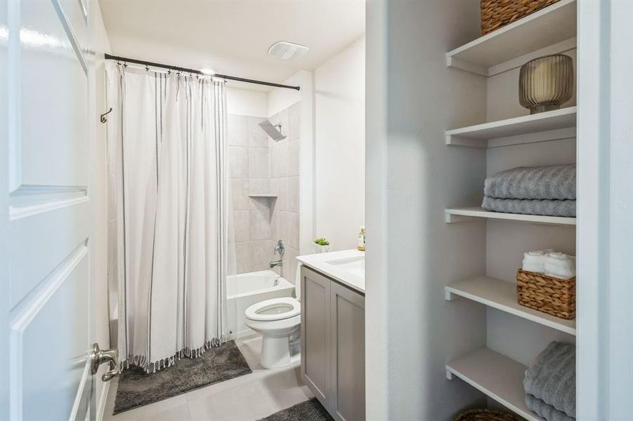 Full bathroom with toilet, tile patterned flooring, shower / bath combination with curtain, and vanity