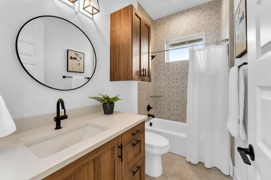 Bathroom with vanity, shower / tub combo, and light tile patterned flooring