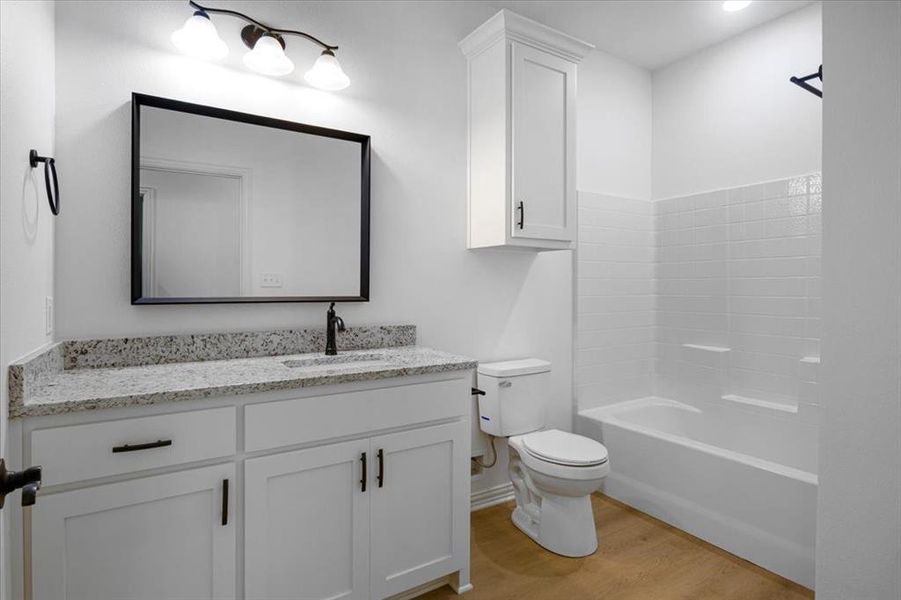 Bathroom with vanity, light wood-type flooring, and shower / washtub combination