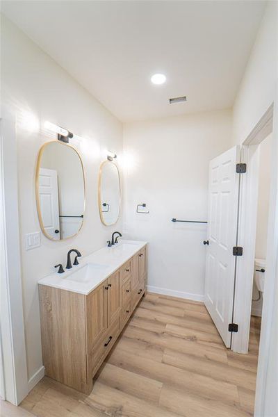 Double vanity with a wood-finish cabinet, white countertop, and integrated sinks