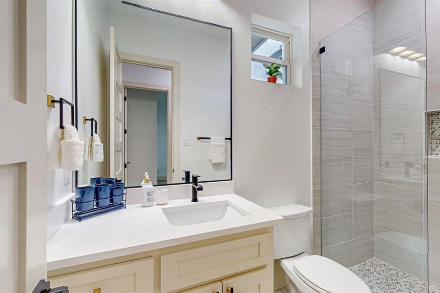 Bathroom featuring vanity, toilet, and a tile shower