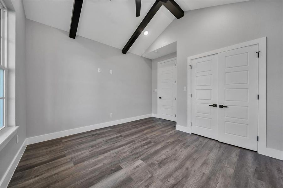 Unfurnished bedroom featuring lofted ceiling with beams, a closet, and dark hardwood / wood-style flooring