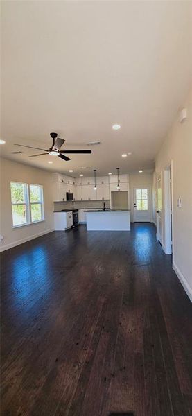 Unfurnished living room with a ceiling fan, healthy amount of natural light, and dark wood finished floors Unfurnished living room with a ceiling fan, healthy amount of natural light, and dark wood finished floors
