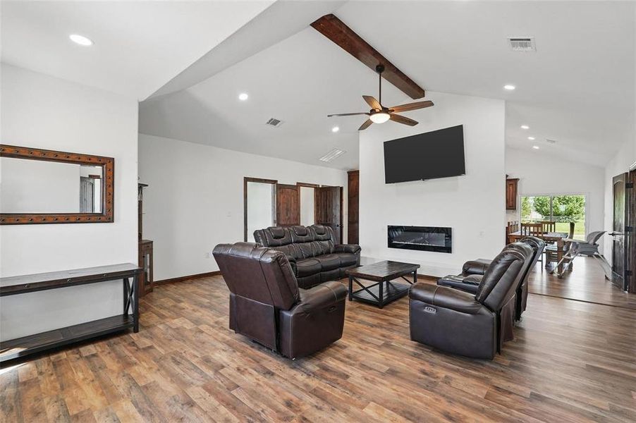 Living room featuring beam ceiling, recessed lighting, a glass covered fireplace, dark wood finished floors, and ceiling fan Living room featuring beam ceiling, recessed lighting, a glass covered fireplace, dark wood finished floors, and ceiling fan