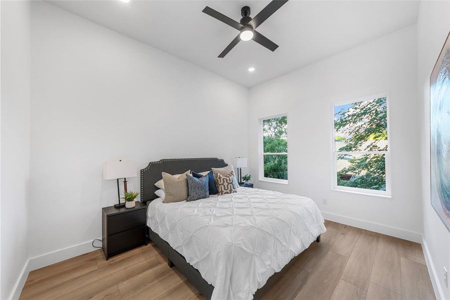 Bedroom with light wood finished floors, recessed lighting, and a ceiling fan Bedroom with light wood finished floors, recessed lighting, and a ceiling fan