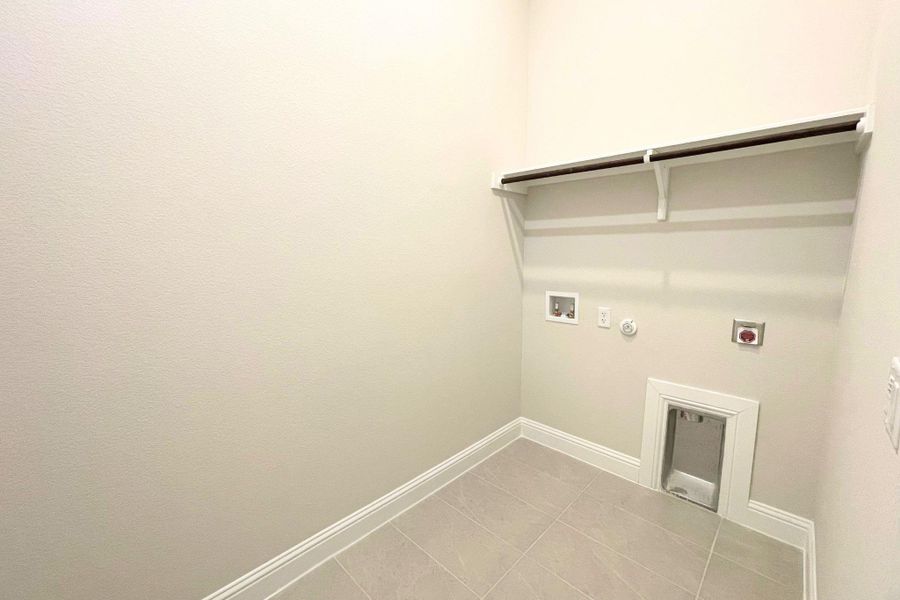 Tiled flooring and neutral walls define this functional utility space complete with overhead shelving. Tiled flooring and neutral walls define this functional utility space complete with overhead shelving.