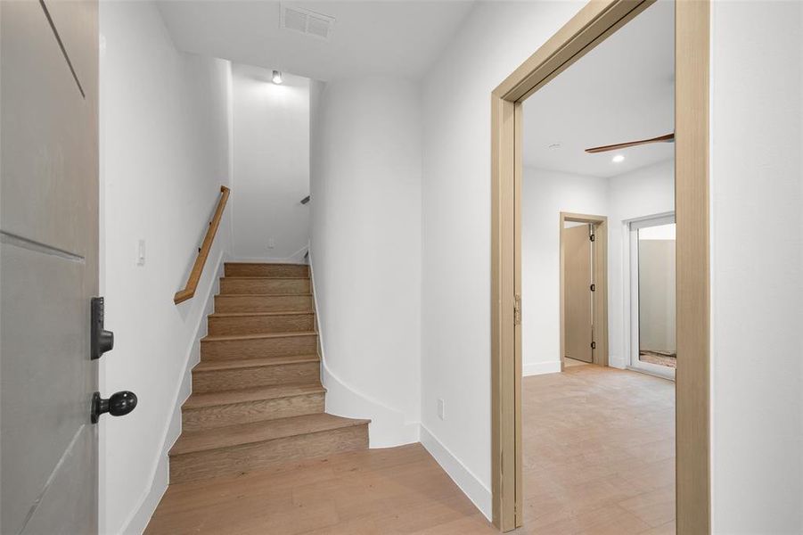 Stairway with wood finished floors and recessed lighting
