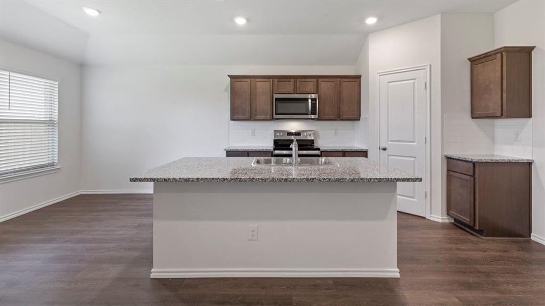 Kitchen featuring a spacious island with a double basin sink and granite-style countertop