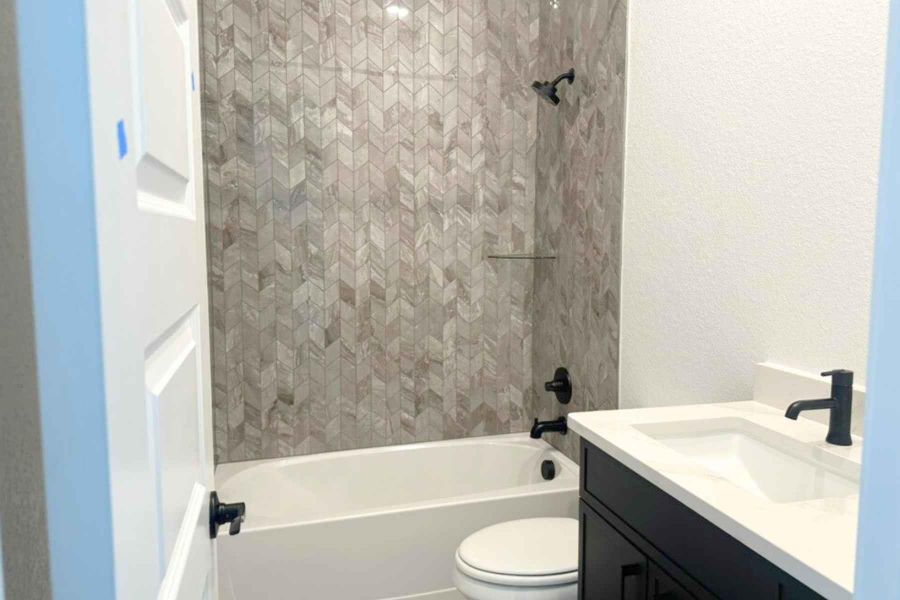Full bath featuring a textured wall, vanity, and bathing tub / shower combination Full bath featuring a textured wall, vanity, and bathing tub / shower combination