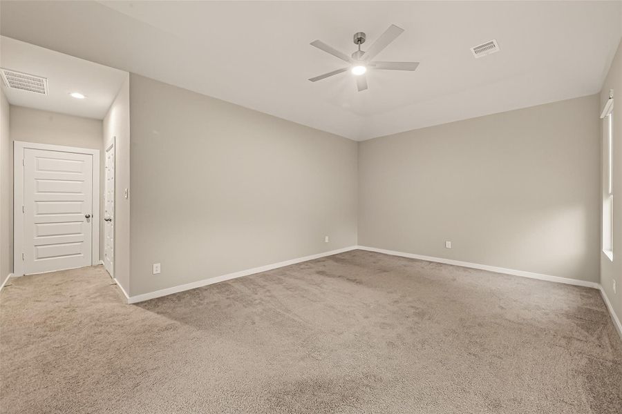An additional view of the main bedroom highlights the spacious layout and natural light from the windows.