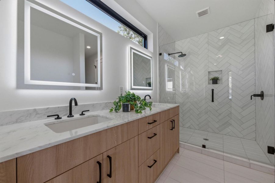Bathroom with double vanity, light tile patterned flooring, and a stall shower