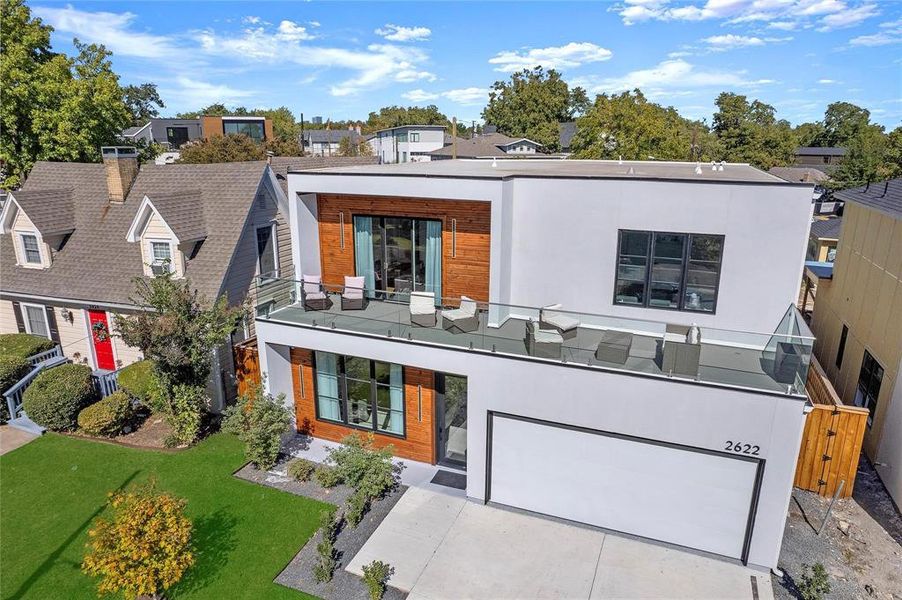 View of front of home with a balcony, a front yard, and a garage