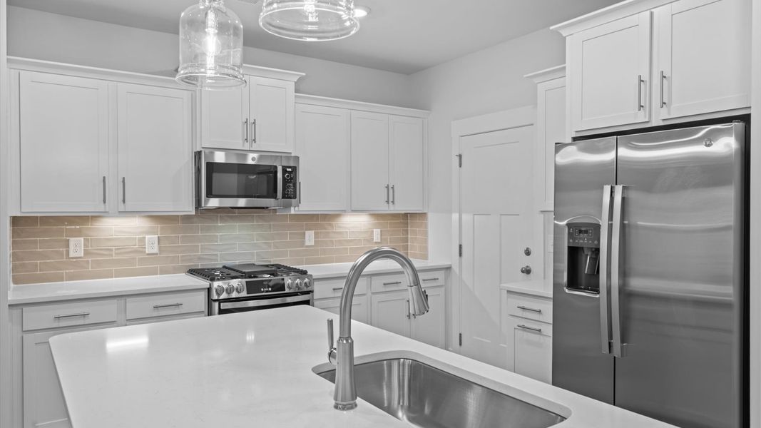 Memorable meals begin in this vibrant kitchen with pendant lighting and a thoughtfully designed island