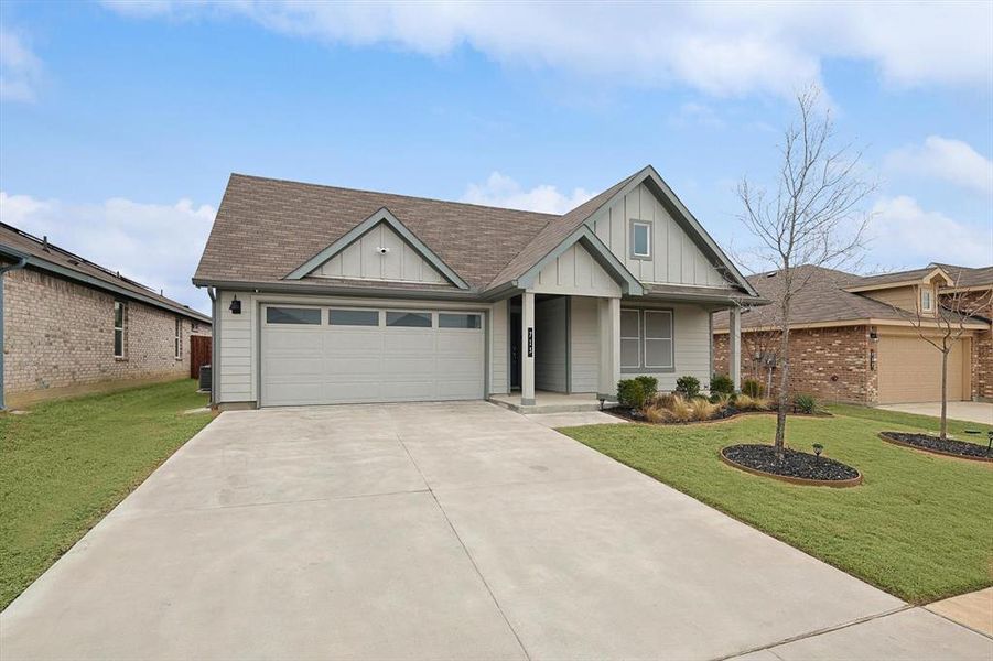 View of front facade featuring a garage, a front lawn, and board and batten siding