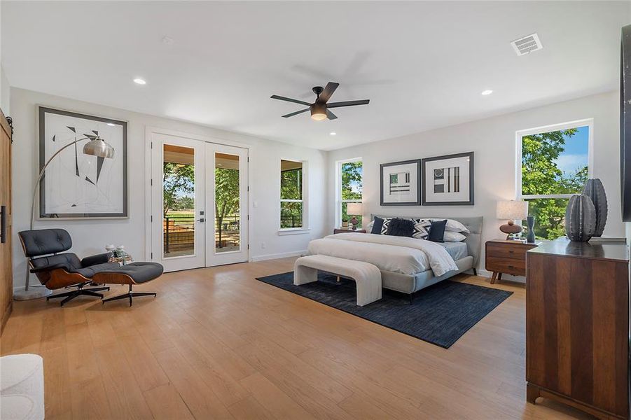 Primary Bedroom with multiple windows, access to exterior, light wood-type flooring, and ceiling fan