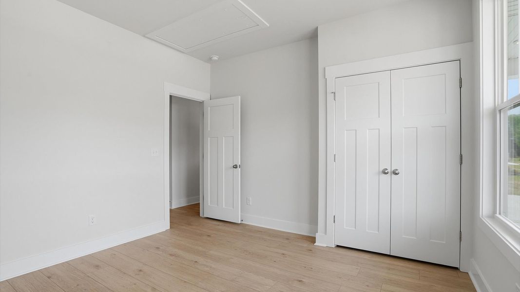 Notable bedroom offering hardwood floors, a walk-in closet, and expansive windows overlooking the yard in Greenville, SC