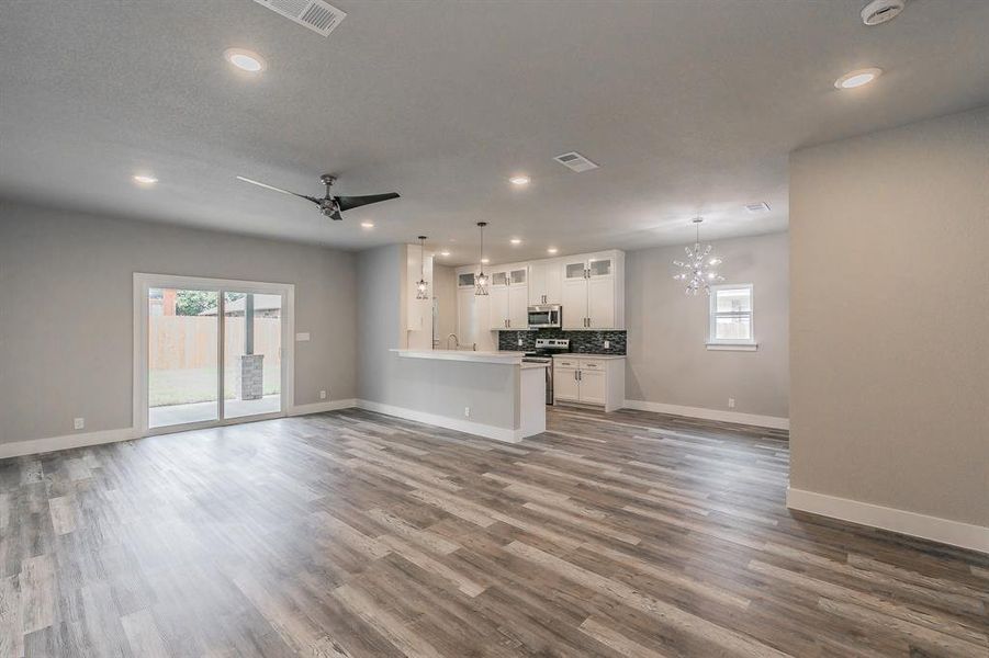 Unfurnished living room featuring sink, hardwood / wood-style flooring, and ceiling fan with notable chandelier