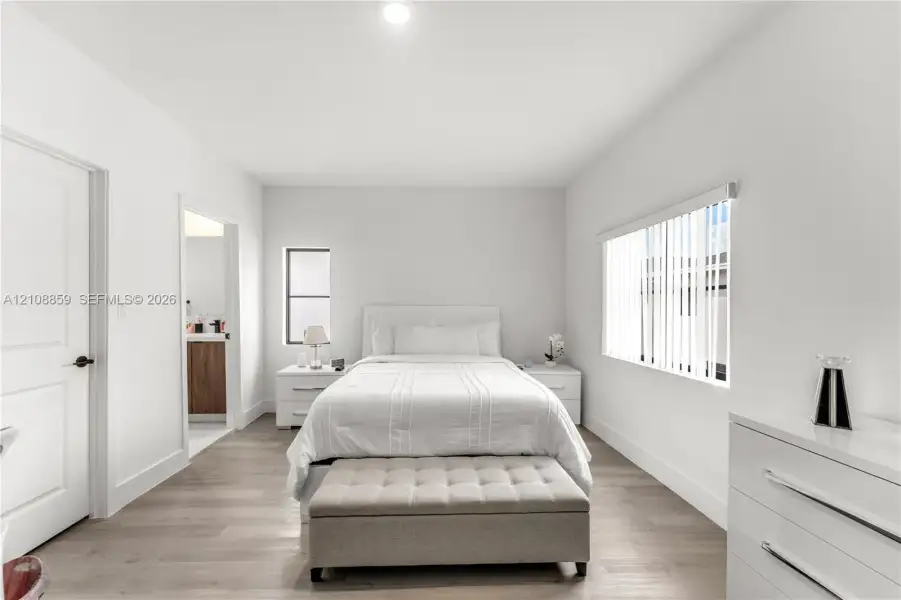 Neutral-toned wood-finish flooring, recessed ceiling lighting, and vertical window blinds