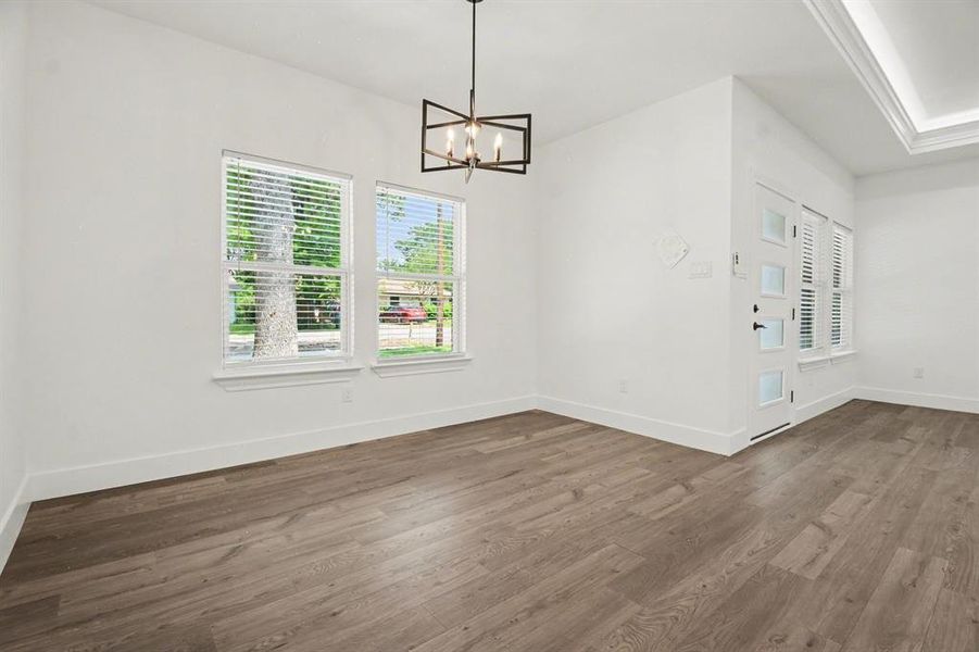 This inviting room features wood-style flooring, a modern chandelier, and two large windows with blinds
