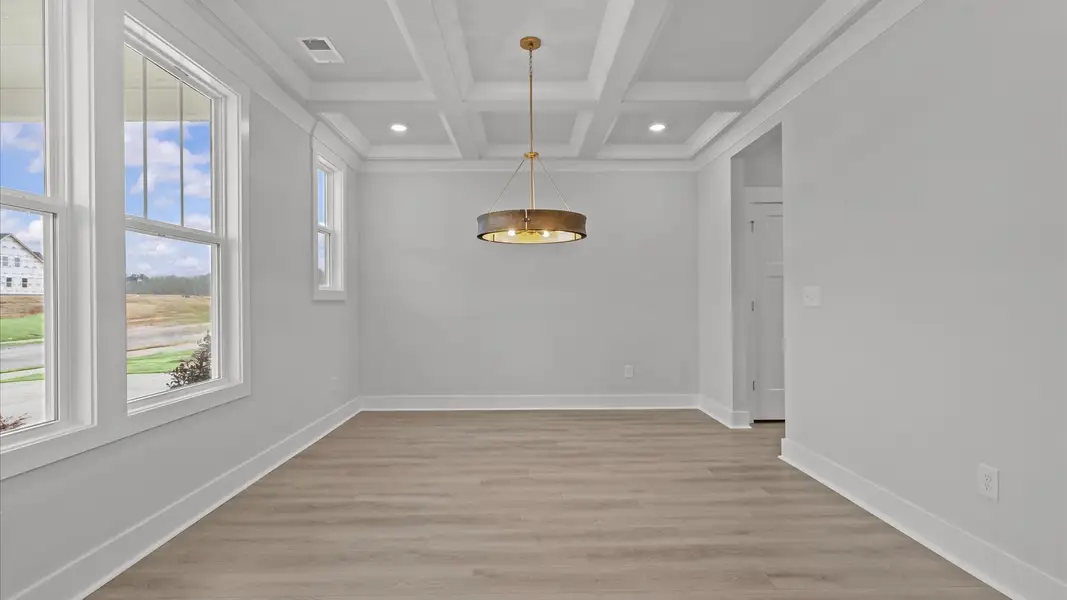Desirable dining room with coffered ceiling and modern elegance in an established community
