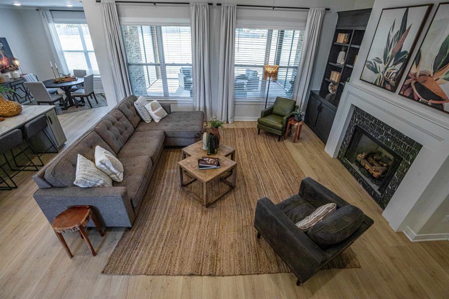 Open-concept living area featuring wood-finish flooring, a fireplace with a dark tile surround and white mantel, and built-in shelving