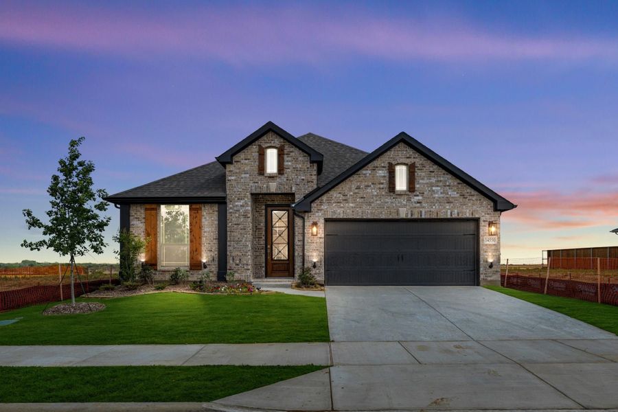 Single-story brick home with dark roof, two-car garage, and manicured front lawn at dusk Single-story brick home with dark roof, two-car garage, and manicured front lawn at dusk