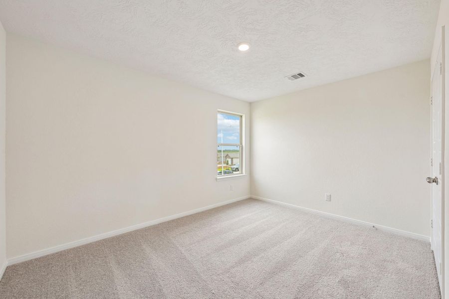 This secondary bedroom offers comfort and style with plush carpeting, neutral paint tones, recessed lighting, large window, and a generously sized closet.