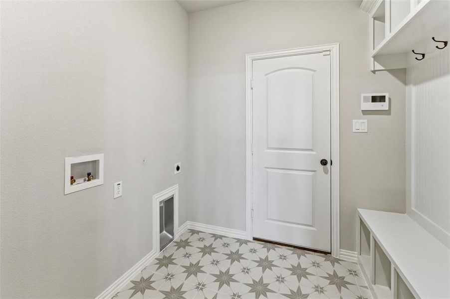 Laundry area featuring star-patterned floor tile, a built-in mudroom bench with cubbies, and overhead shelving with coat hooks