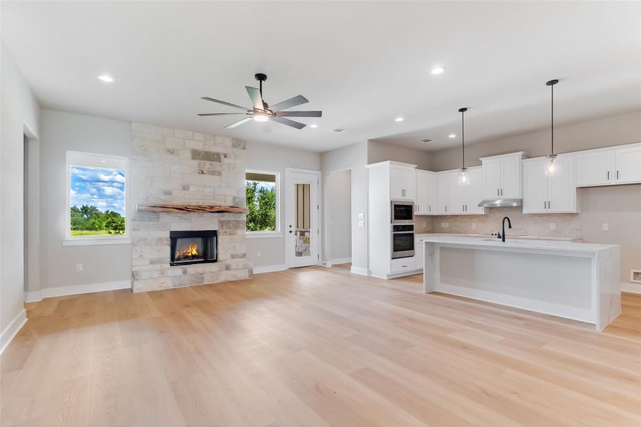 Unfurnished living room with ceiling fan, recessed lighting, a fireplace, and light wood-style floors