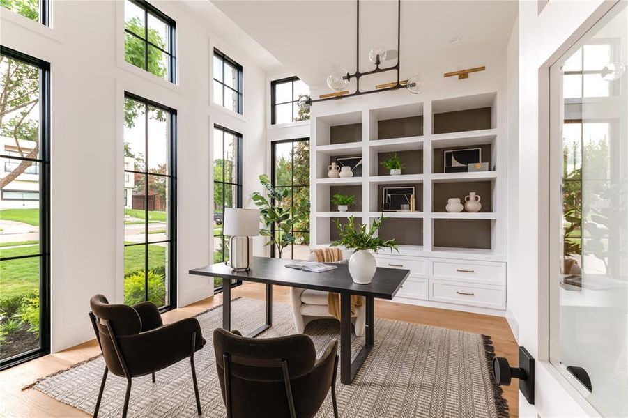 Office space with light wood-style floors, a chandelier, and a high ceiling