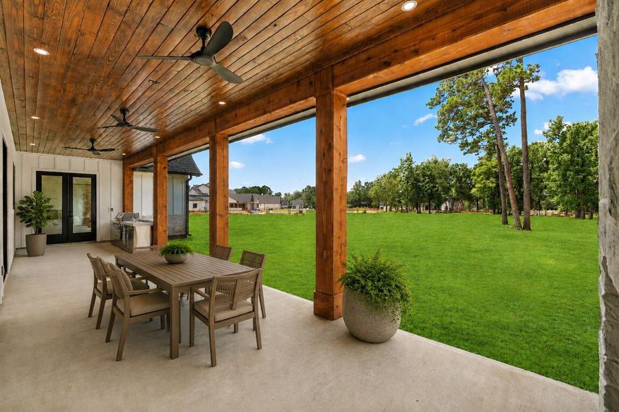 Expansive covered patio featuring a full outdoor kitchen, tongue and groove-stained wood ceiling overlooking the peaceful, wooded views. Expansive covered patio featuring a full outdoor kitchen, tongue and groove-stained wood ceiling overlooking the peaceful, wooded views.