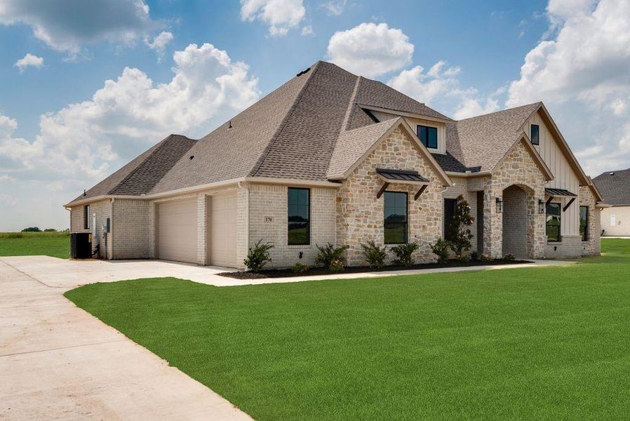 French provincial home featuring a shingled roof, an attached garage, driveway, and a front yard French provincial home featuring a shingled roof, an attached garage, driveway, and a front yard