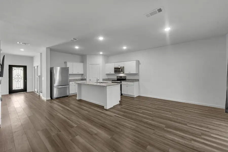 Vinyl plank flooring runs from the entry through the kitchen and family room