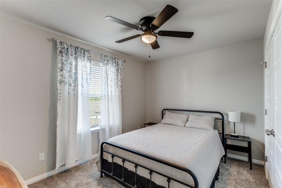 Bedroom with light carpet and a ceiling fan