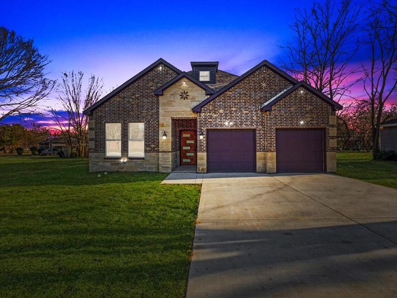 French country home with an attached garage, driveway, brick siding, stone siding, and a yard French country home with an attached garage, driveway, brick siding, stone siding, and a yard