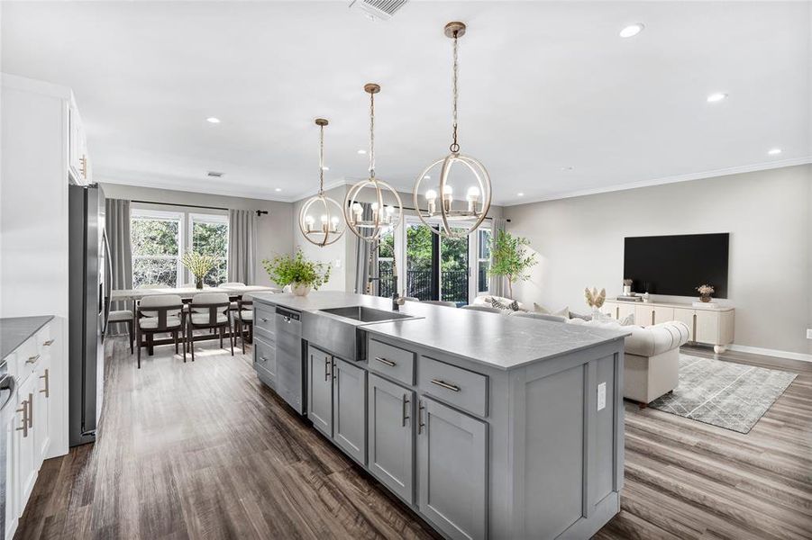 Kitchen with an island with sink, dark wood-style flooring, appliances with stainless steel finishes, open floor plan, and a chandelier