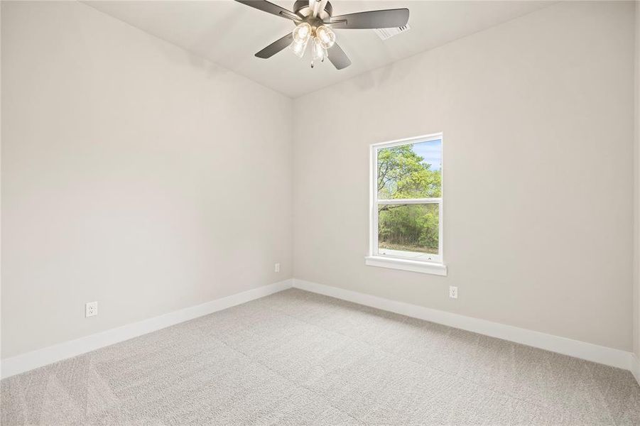 Carpeted empty room with baseboards and a ceiling fan Carpeted empty room with baseboards and a ceiling fan