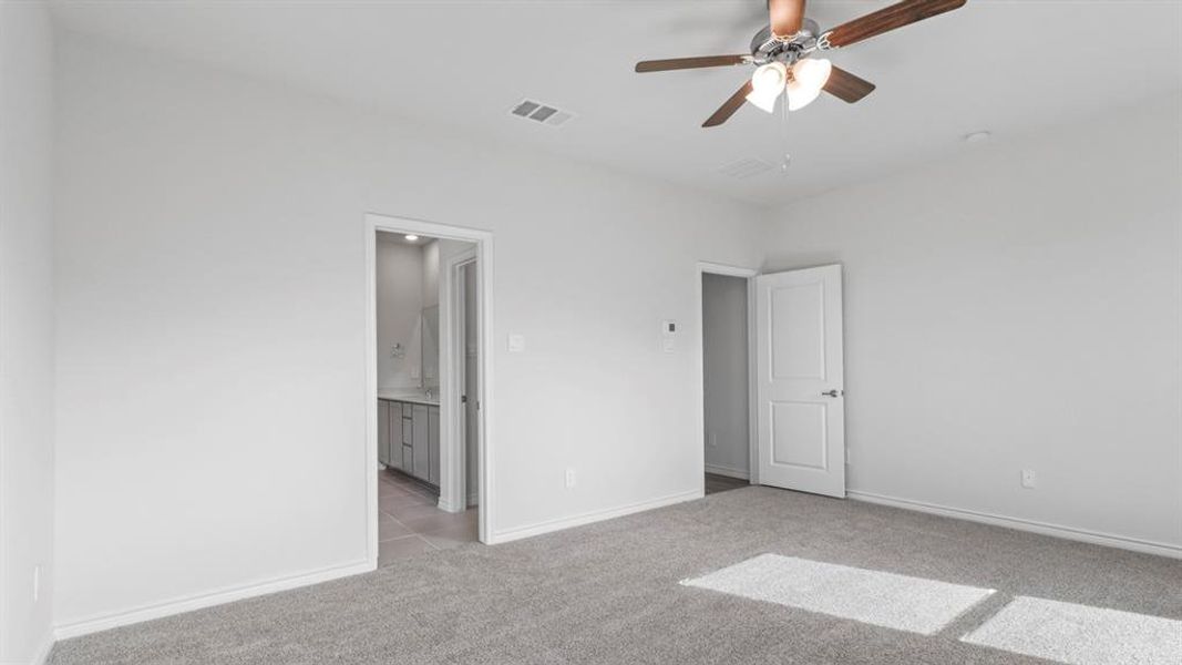 Unfurnished bedroom featuring light colored carpet, ceiling fan, and ensuite bath