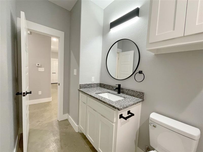 Bathroom featuring concrete floors, vanity, and toilet