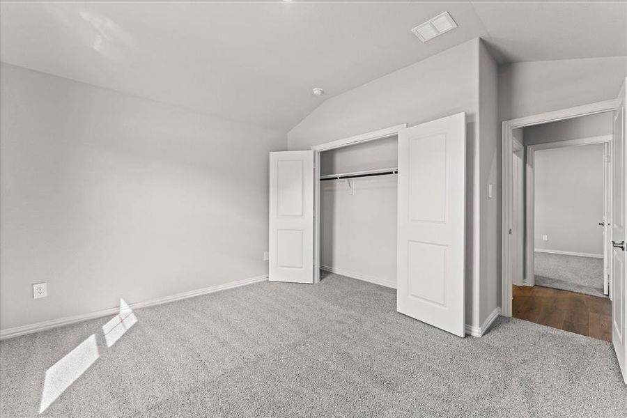 Unfurnished bedroom with light carpet, lofted ceiling, and a closet