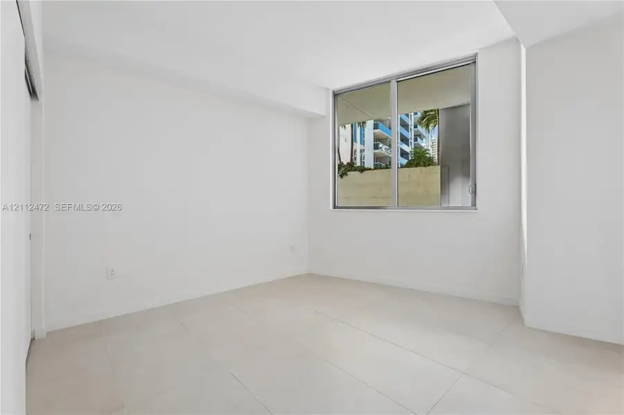 Minimalist interior featuring large-format ceramic tile flooring, neutral wall finishes, and a sizable window with aluminum framing