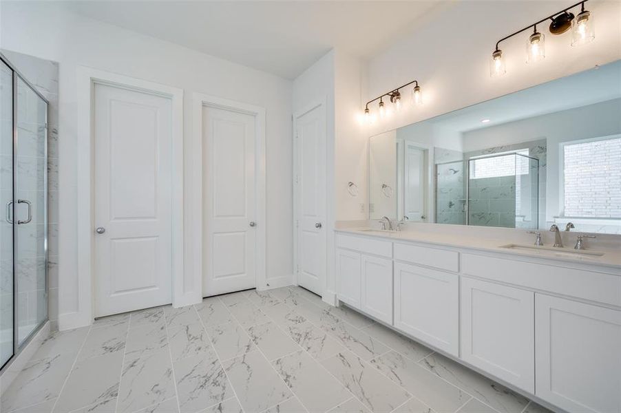 Bathroom featuring tile patterned flooring, double sink vanity, and a shower with shower door